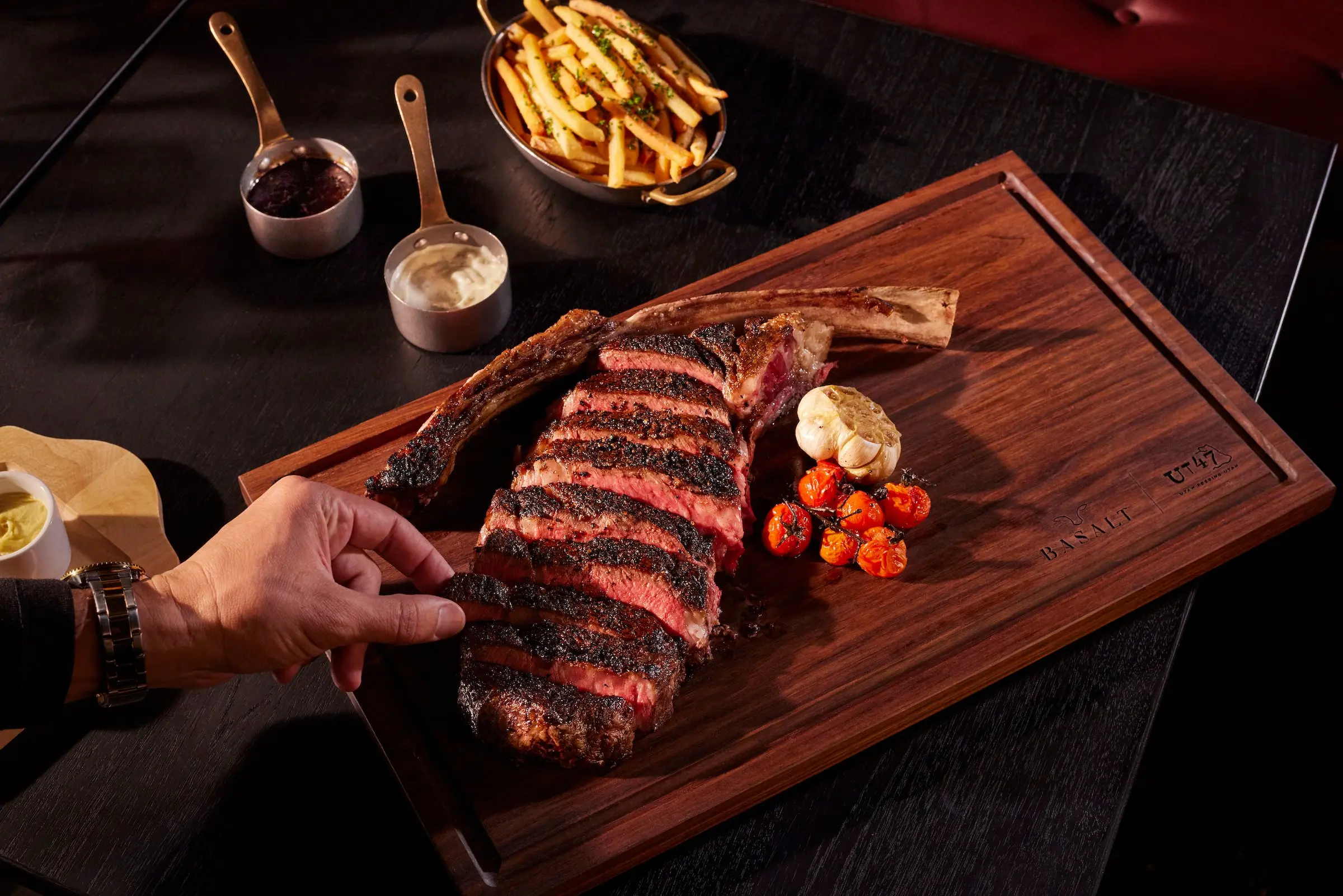 A steak sliced on a wood board with butter and cherry tomatoes at Black Desert Resort