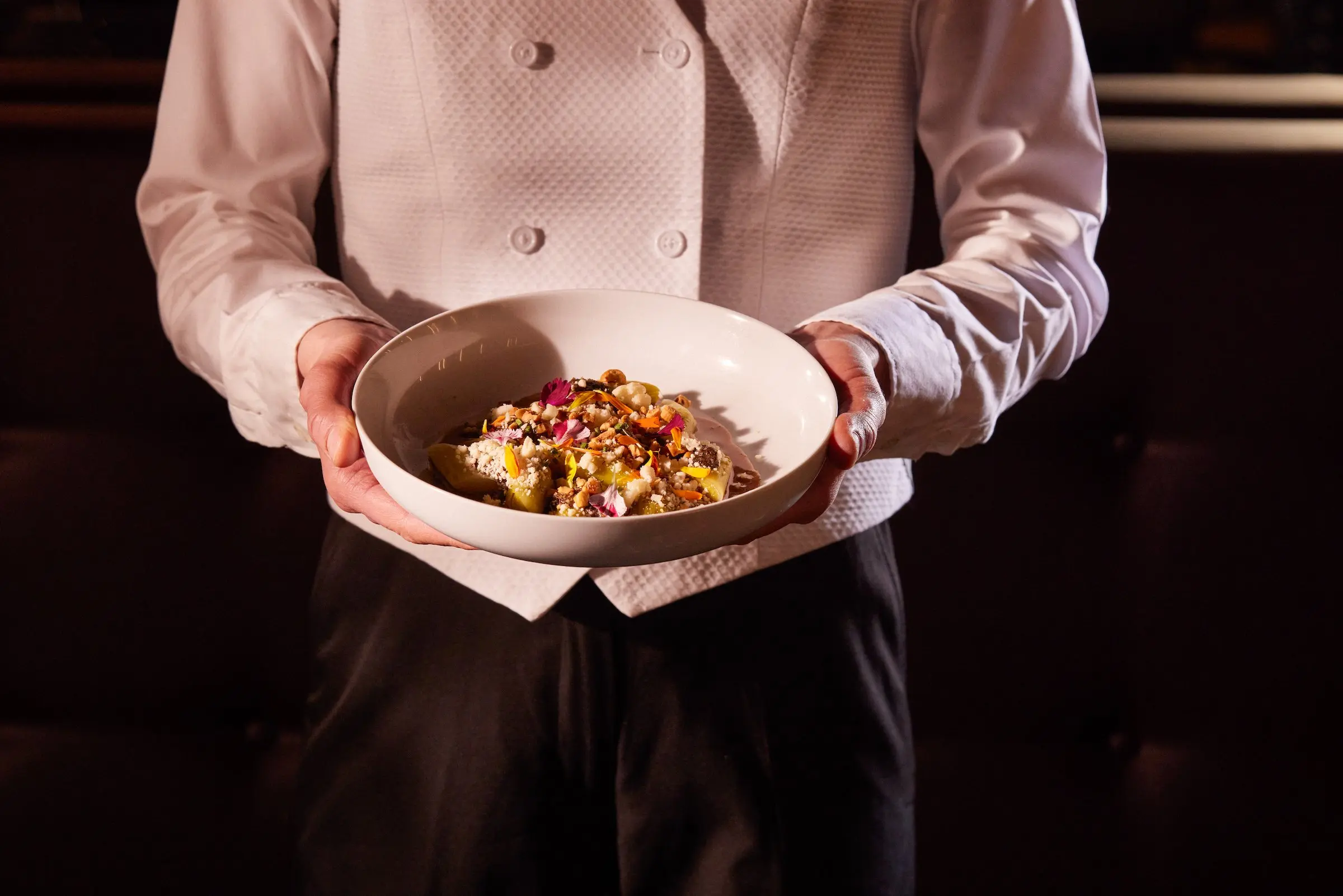 A server holding a dish at a restaurant at Black Desert Resort