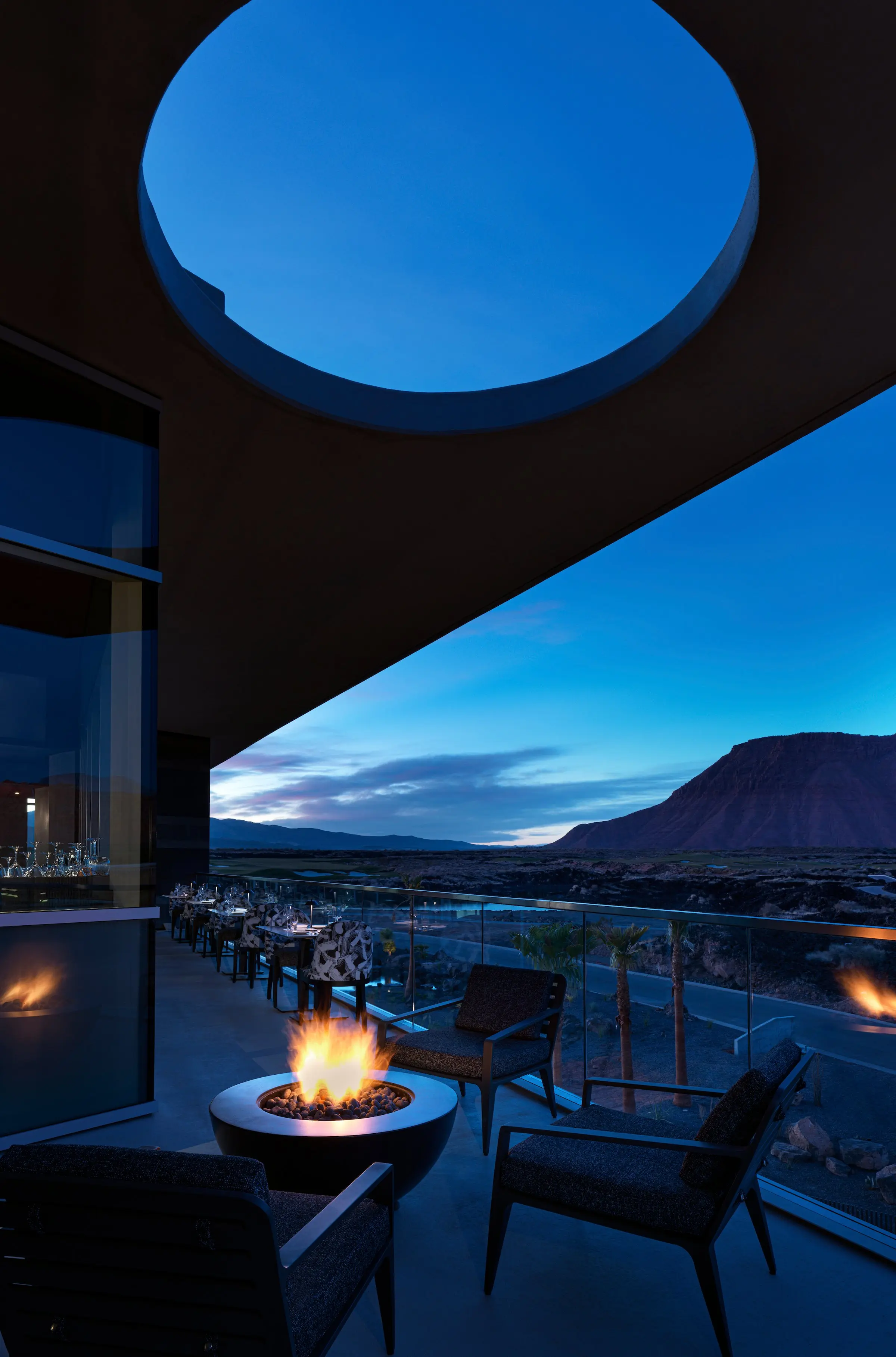 The elegant dining room of the fine dining restaurant at Black Desert Resort, featuring floor-to-ceiling windows with panoramic views of the golf course and mountains.