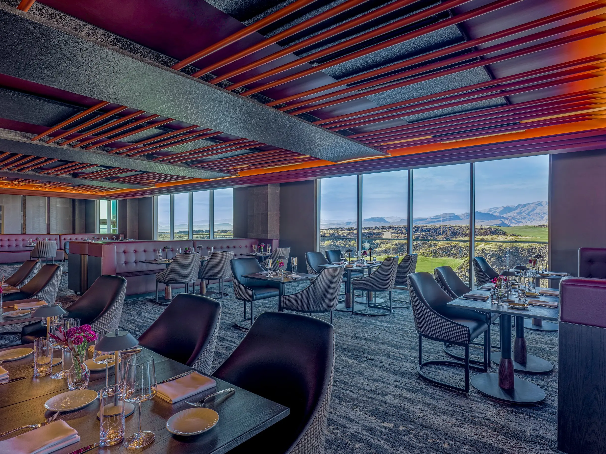 The elegant dining room of the fine dining restaurant at Black Desert Resort, featuring floor-to-ceiling windows with panoramic views of the golf course and mountains.