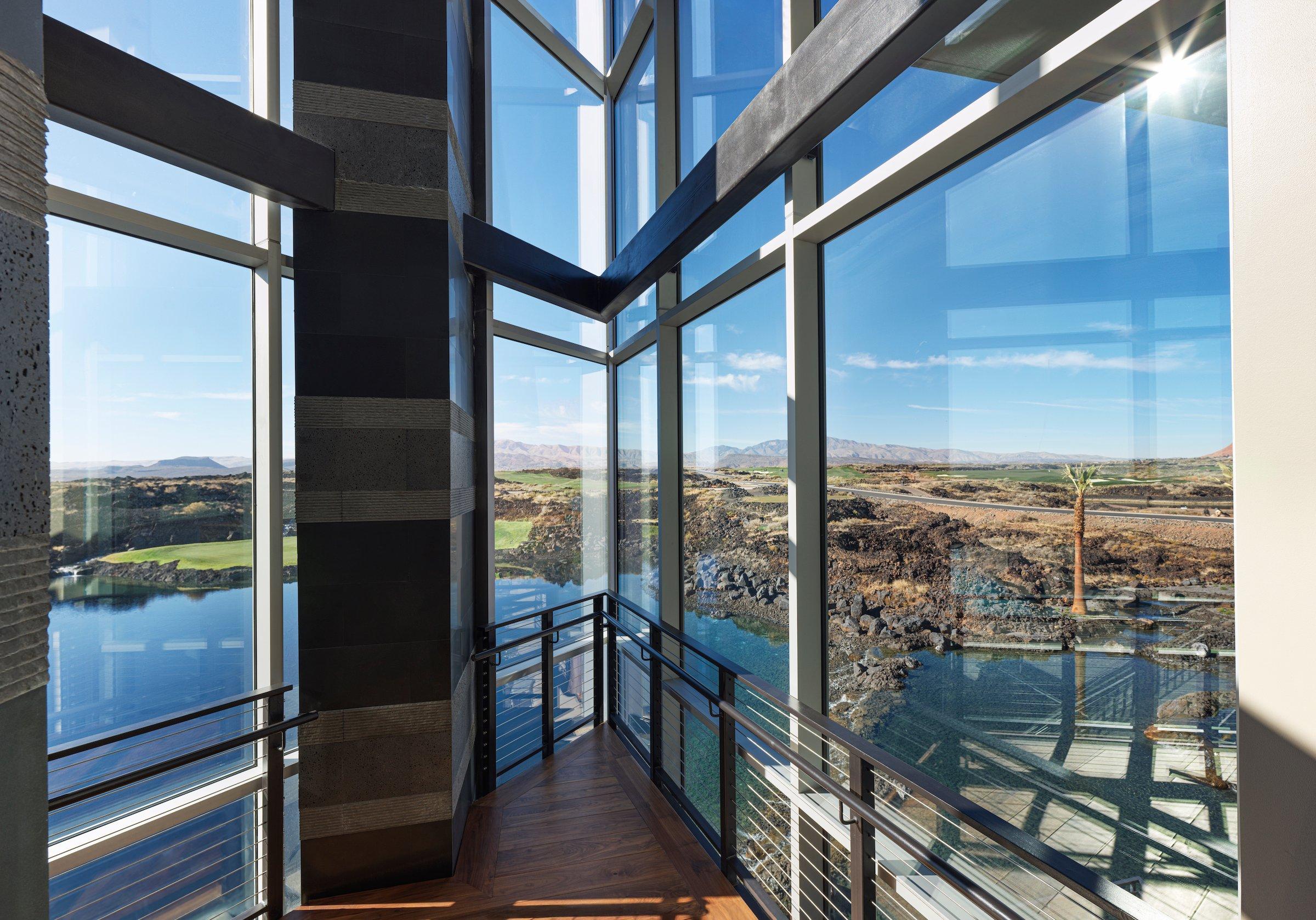 The elegant dining room of the fine dining restaurant at Black Desert Resort, featuring floor-to-ceiling windows with panoramic views of the golf course and mountains.