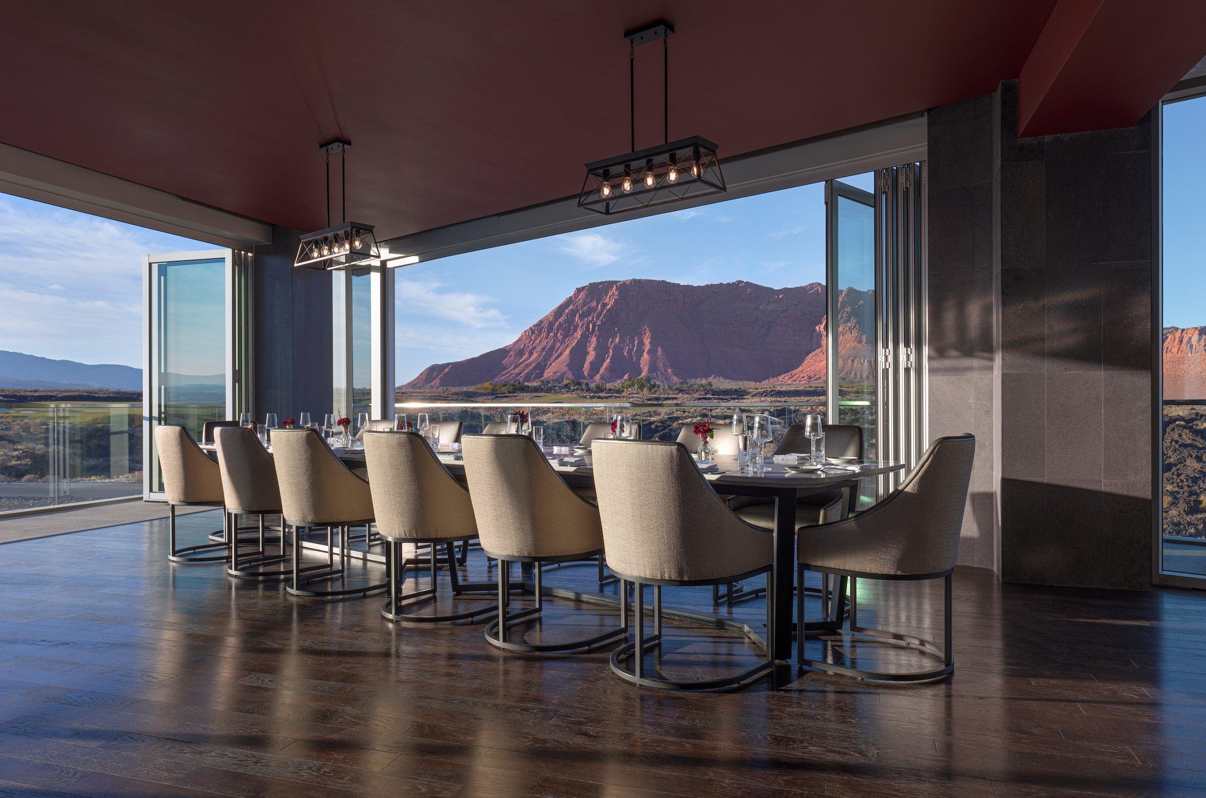 The elegant dining room of the fine dining restaurant at Black Desert Resort, featuring floor-to-ceiling windows with panoramic views of the golf course and mountains.