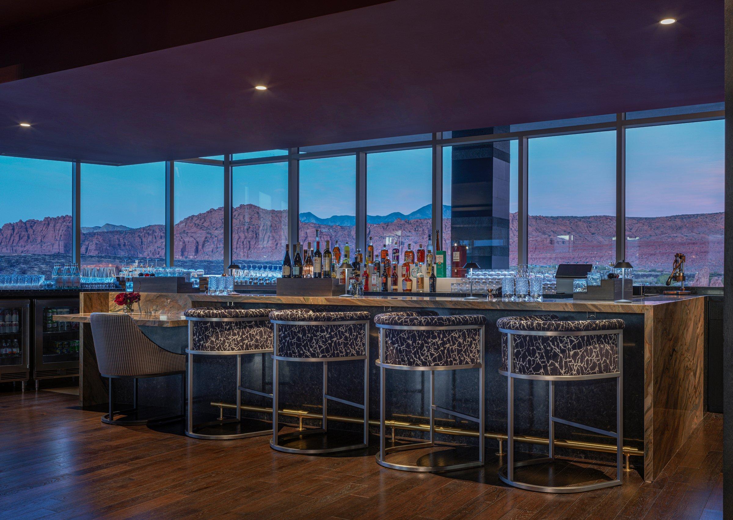 The elegant dining room of the fine dining restaurant at Black Desert Resort, featuring floor-to-ceiling windows with panoramic views of the golf course and mountains.