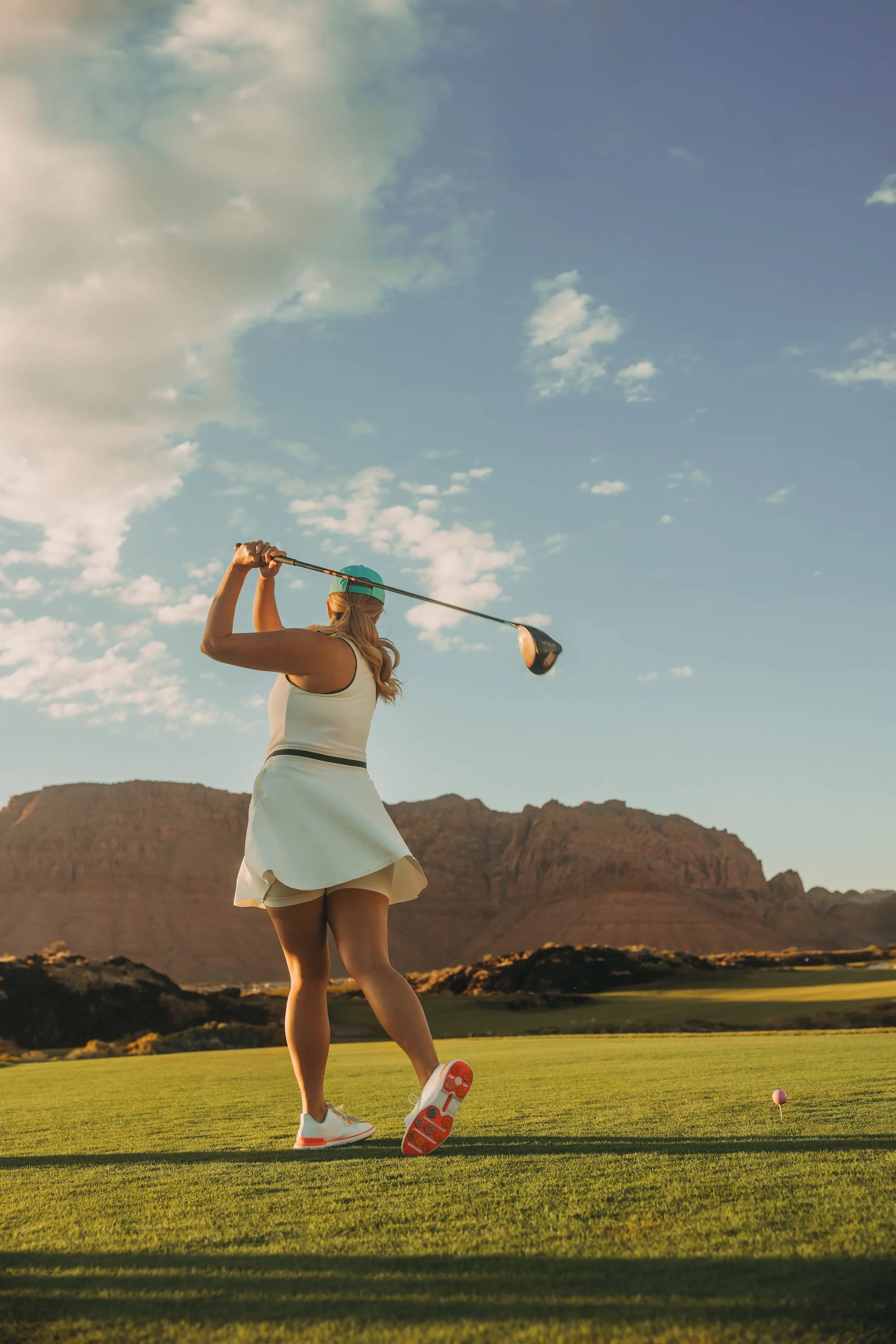 A woman in an after golf swing position looking at where the ball went at Black Desert Resort