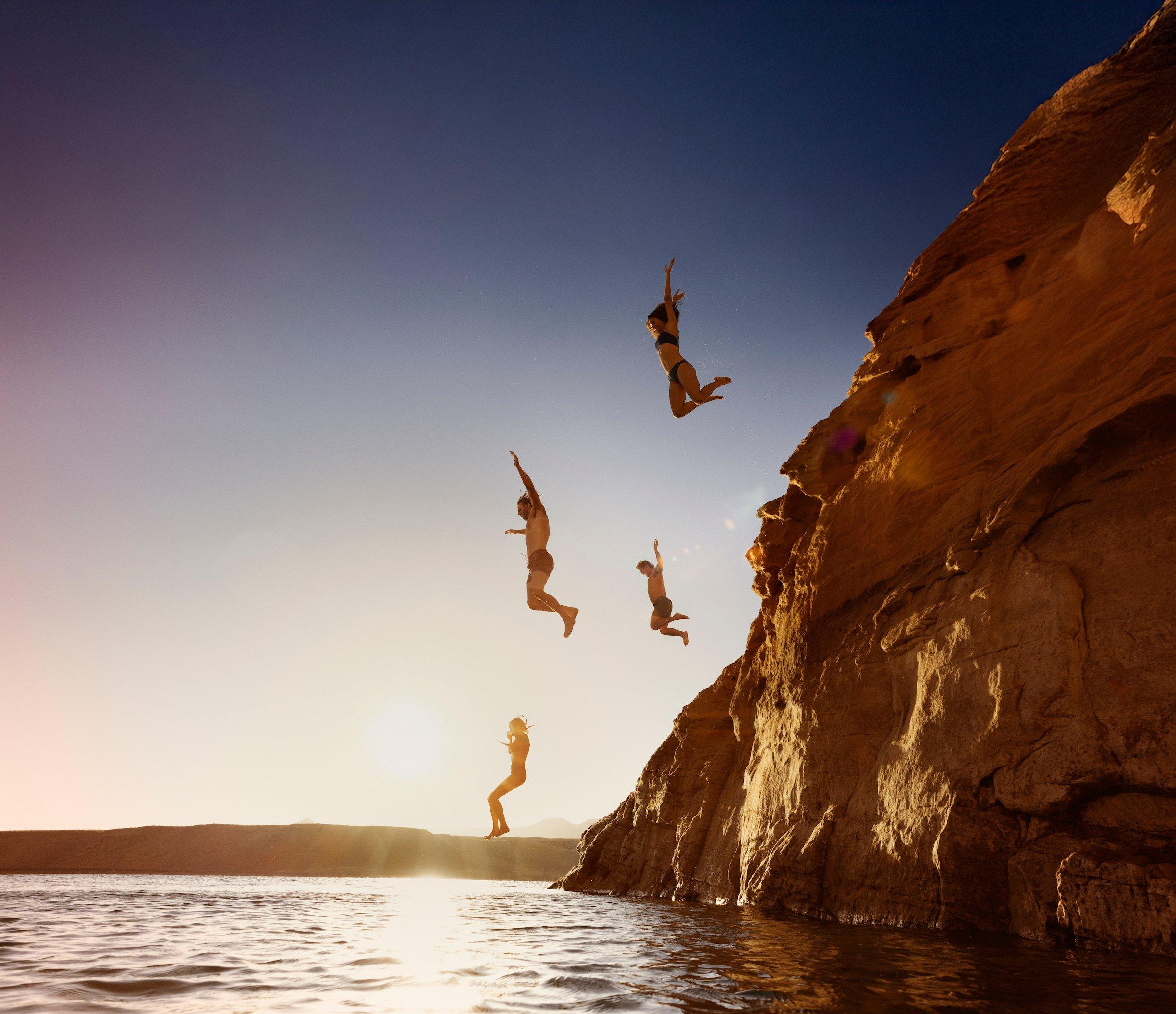 A bunch of people jumping off a mountain into water at Black Desert Resort