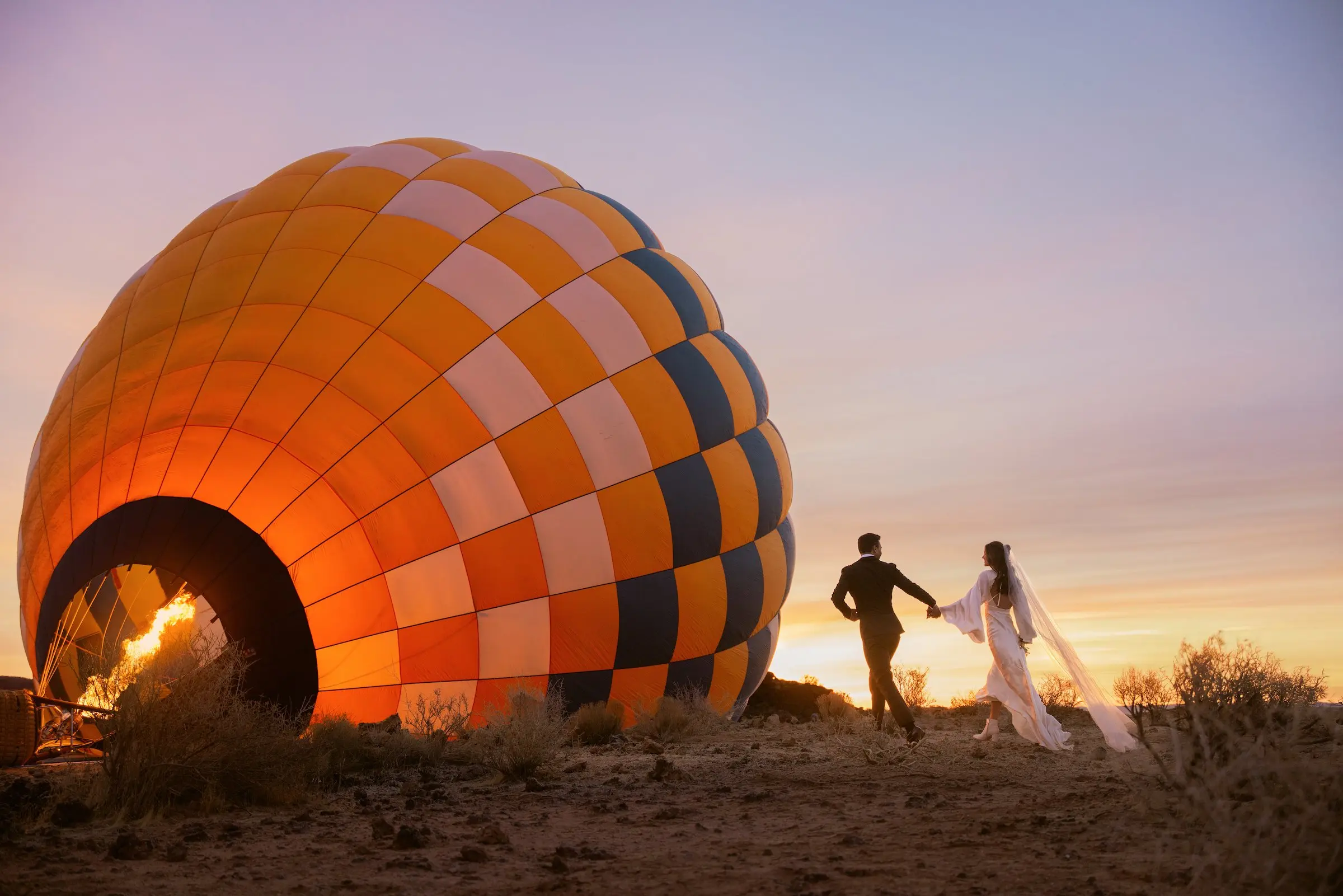 A bride and groom celebrate their destination wedding at Black Desert Resort with a romantic hot air balloon experience at sunset.